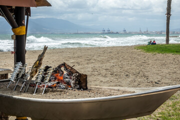 Wall Mural - Typical food of the Andalusian coast: Sardines, octopus and fish roasting by a coal fire in a boat