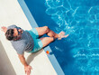 Fashionable man sitting by the pool  on the empty deck of a cruise liner. Closeup, outdoor. Vacation and travel concept