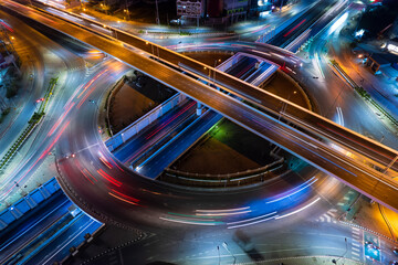 Poster - Aerial view of car traffic transportation above circle roundabout road in Asian city. Drone aerial view fly in circle, high angle. Public transport or commuter city life concept of economic and energ