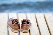 Shoes Left On A Wooden Pier. Brown Shoes By The Lake