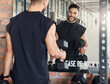 © Nicholas Felix/peopleimages.com - Workout to impress yourself. Shot of a sporty young man looking at himself in a mirror while exercising with dumbbells in a gym.