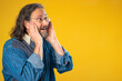© Robert Peak - Promoter senior long haired bearded man 50s 60s blue shirt looking aside on workspace copy space mockup promo commercial area isolated on solid yellow background studio portrait