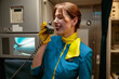 Cheerful flight attendant talking on telephone in airplane