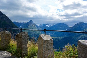 Wall Mural - view over mountains and the geiranger fjord in the valley behind a fence with granite stones in møre