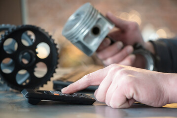 Wall Mural - Worker is calculating the price of car spare parts with calculator concept. Car repair cost estimate.