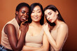 © iordani - young pretty asian, caucasian, african woman posing cheerful together on brown background, lifestyle diverse nationality people concept