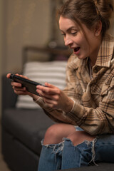 Poster - Girl gamer emotionally plays a video game on a portable game console. Close-up. Virtual reality, mobile games, cyberspace, youth culture, competition, prizes, win.