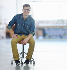 I dont need a desk to excel. Portrait of a smiling young designer sitting on a chair in a large office.