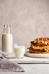 Wall Mural - Fresh homemade sweet belgian waffles with honey and powdered sugar stacked on white round marble board