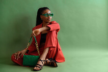 Fashionable Elegant Black Woman Wearing Trendy Green Sunglasses, Orange Suit With Blazer, Trousers, Strap Sandals, Leather Bag. Full-length Studio Portrait With Natural Day Light. Copy Space For Text