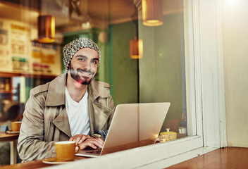 Canvas Print - Hanging out at his favorite cafe. Portrait of a stylish young man smiling while drinking a coffee and using a laptop in a cafe.