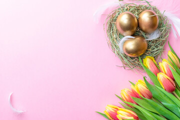 Wall Mural - Easter Golden eggs in basket with spring tulips, white feathers on pastel pink background in Happy Easter decoration. Spring holiday flat lay concept.