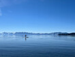 Man paddle boarding on a serene lake with snow-capped mountains. Lake Tahoe