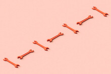 Three Dimensional Render Of Row Of Orange Colored Wrenches Flat Laid Against Beige Background
