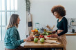 © Westend61 - Happy young woman talking with friend sitting at table in kitchen