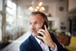 © Westend61 - Senior businessman talking on mobile phone in cafe