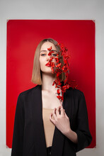 Blond Woman Holding Twig In Front Of Blank Red Frame Against White Background