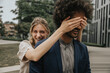 © Westend61 - Happy young woman covering boyfriend's eyes with hand in front of modern building