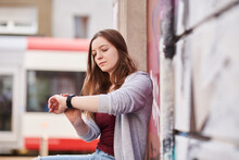 Young Woman Checking The Time Sitting In The City
