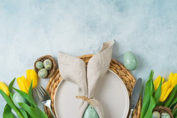 Wall Mural - Easter festive table setting with easter eggs decoration and yellow tulips flowers on gray background. Top view, flat lay