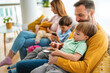 © NDABCREATIVITY - Parents with children playing games, using mobile apps on phone at home