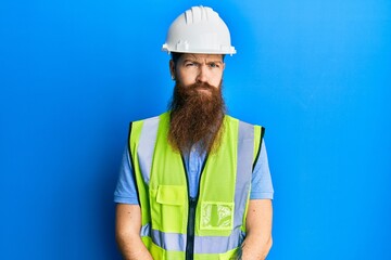 Wall Mural - Redhead man with long beard wearing safety helmet and reflective jacket depressed and worry for distress, crying angry and afraid. sad expression.