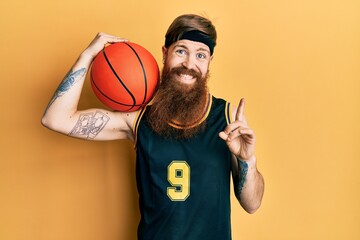 Poster - Redhead man with long beard wearing basketball uniform holding ball smiling happy pointing with hand and finger to the side