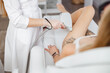 © Friends Stock - Female cosmetologist performing laser treatment on woman leg
