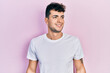 © Krakenimages.com - Young hispanic man wearing casual white t shirt looking to side, relax profile pose with natural face and confident smile.