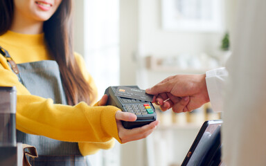 Customer using credit card for payment to owner at cafe restaurant, cashless technology and credit card payment concept