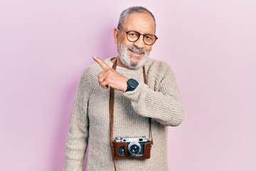 Canvas Print - Handsome senior man with beard holding vintage camera smiling cheerful pointing with hand and finger up to the side