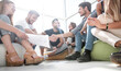 © ASDF - friends shaking hands, sitting on the floor in the new office