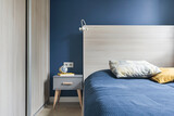Fototapeta  - Niebieska sypialnia z dużym łózkiem, pojemnymi szafami na ubrania oraz akcesoriami wnętrzarskimi