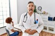 © Krakenimages.com - Middle age doctor man at the clinic with a patient sticking tongue out happy with funny expression. emotion concept.