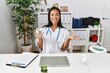 © Krakenimages.com - Young latin woman wearing doctor uniform holding pills at clinic