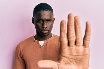 Young african american man wearing casual clothes doing stop sing with palm of the hand. warning expression with negative and serious gesture on the face.