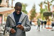 © Krakenimages.com - Young african american man using smartphone drinking coffee at the city