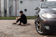 © alones - Young stylish man hipster with a phone sits on a longboard near his car. A summer evening and vacation