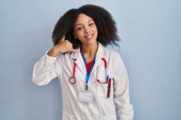 Wall Mural - Young african american woman wearing doctor uniform and stethoscope smiling doing phone gesture with hand and fingers like talking on the telephone. communicating concepts.