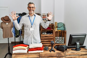 Sticker - Middle age hispanic man working as manager at retail boutique showing and pointing up with fingers number ten while smiling confident and happy.