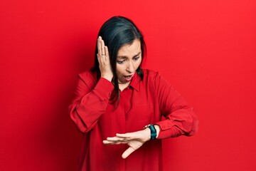 Canvas Print - Middle age hispanic woman wearing casual clothes looking at the watch time worried, afraid of getting late