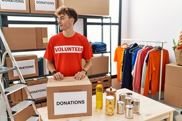 Sticker - Young caucasian man volunteer holding donations box looking to side, relax profile pose with natural face and confident smile.