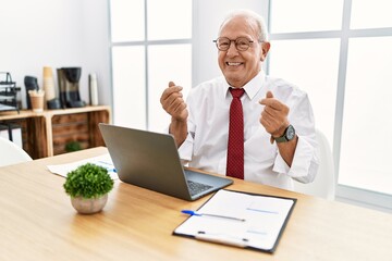 Wall Mural - Senior man working at the office using computer laptop doing money gesture with hands, asking for salary payment, millionaire business