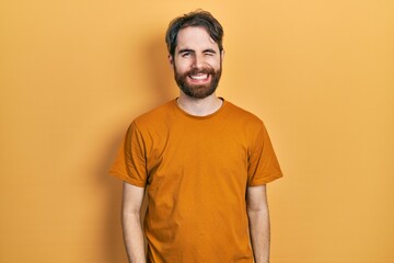 Wall Mural - Caucasian man with beard wearing casual yellow t shirt winking looking at the camera with sexy expression, cheerful and happy face.