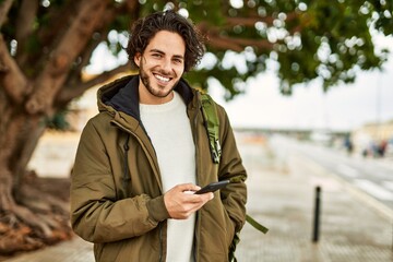 Wall Mural - Handsome hispanic man using smartphone at the city