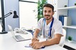 © Krakenimages.com - Young hispanic man wearing doctor uniform writing on document working at clinic