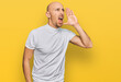 © Krakenimages.com - Bald man with beard wearing casual white t shirt shouting and screaming loud to side with hand on mouth. communication concept.