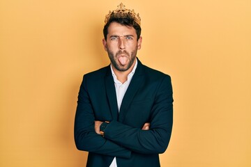 Poster - Handsome man with beard wearing business suit with arms crossed gesture and king crown sticking tongue out happy with funny expression.