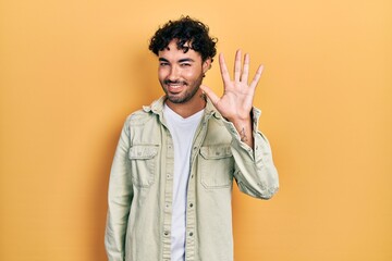 Poster - Young hispanic man wearing casual clothes showing and pointing up with fingers number five while smiling confident and happy.