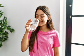 Sticker - Young latin woman smiling confident drinking water at home